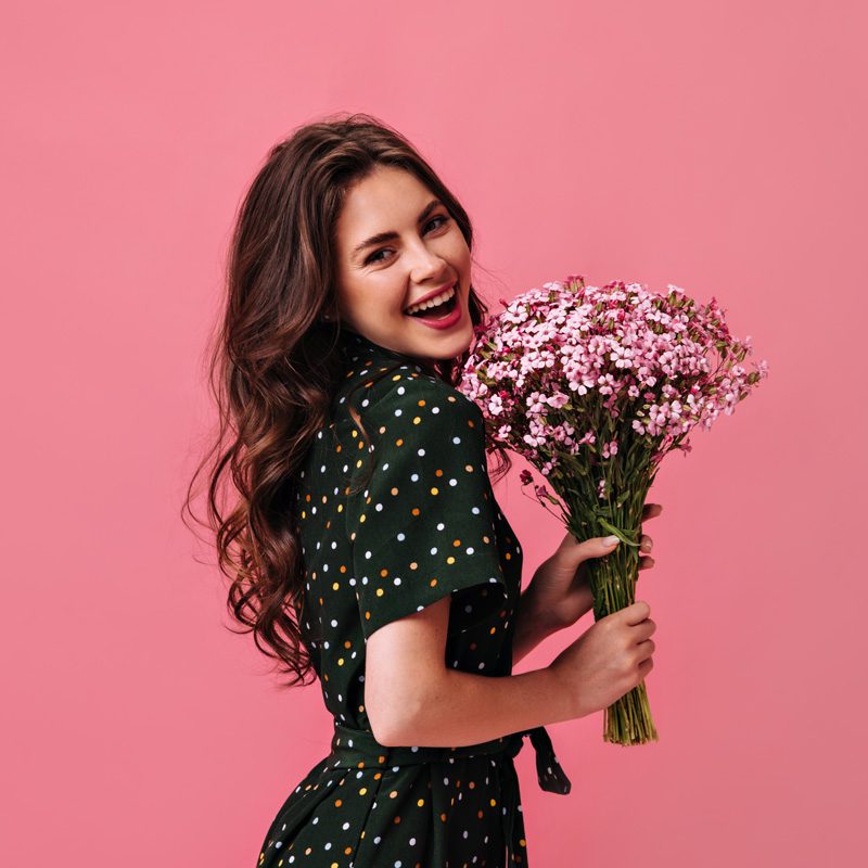 A girl wearing black and holding flowers with red background